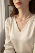 Double-layer white pearl pendant necklace worn with an ivory blouse