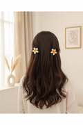 White and yellow acrylic flower hair clips worn in long dark hair