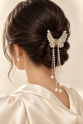 Woman wearing gold butterfly pearl tassel hair claw in a low bun