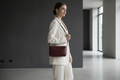 Woman wearing a maroon leather shoulder bag with an ivory tailored outfit