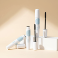 Waterproof black eyelash mascara in white packaging with pale blue details, shown with open applicator on a warm ivory studio background