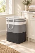 Grey striped laundry basket beside a cabinet in a light laundry room