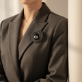 Black pearl and rhinestone brooch pinned to a charcoal blazer lapel