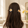 Two cream flower hair claw clips styled in dark brown hair