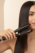 Woman using a black hair straightener to create smooth glossy straight hair