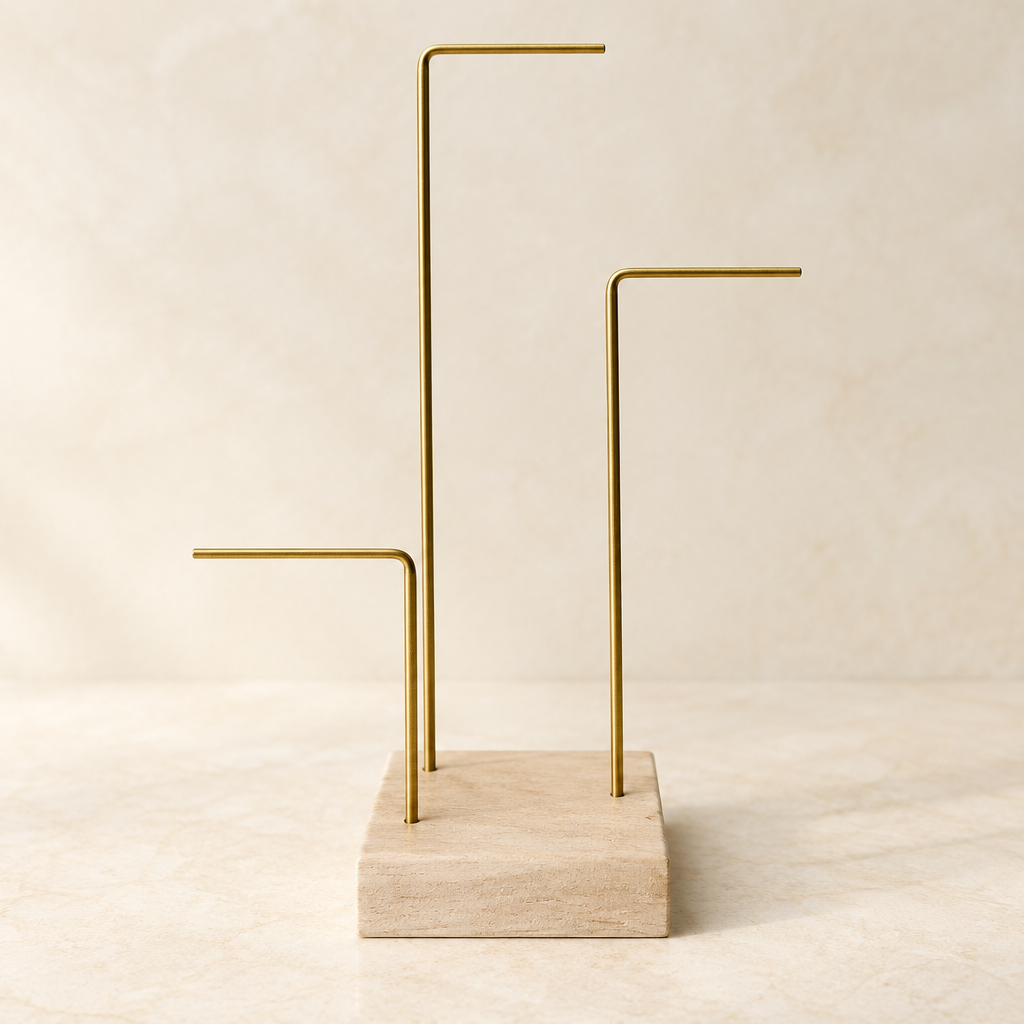Close view of pale wooden base and three gold-tone metal bars of jewelry display stand