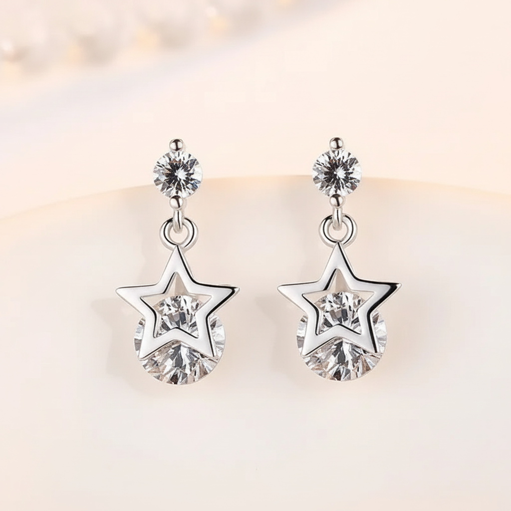 Pair of silver-tone star crystal drop earrings on a warm ivory background