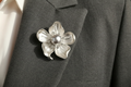 Matte silver pearl and crystal flower brooch pinned to charcoal tailored fabric
