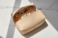 Luxury leather cosmetic bag open flat displaying makeup on marble surface