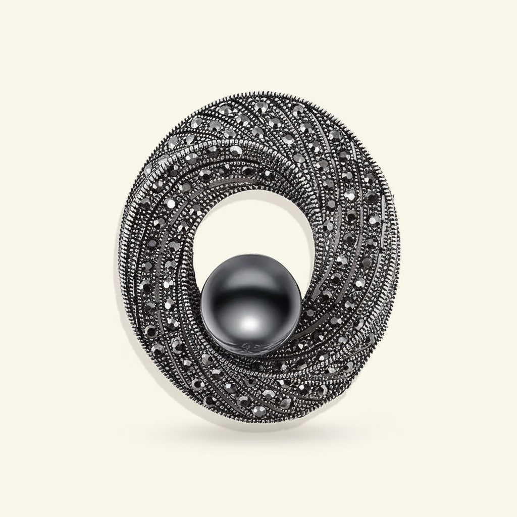 Black pearl and rhinestone swirl brooch on an ivory background