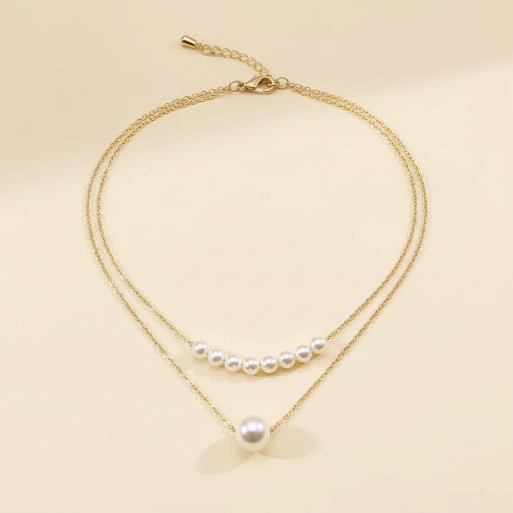 Two-layer gold-plated pearl necklace arranged on a warm ivory background