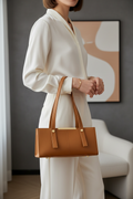 Woman carrying a mustard structured leather shoulder bag by its handles
