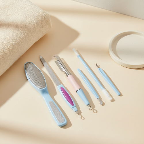 Six-piece multicolor manicure and pedicure kit styled beside a folded towel on a warm ivory vanity