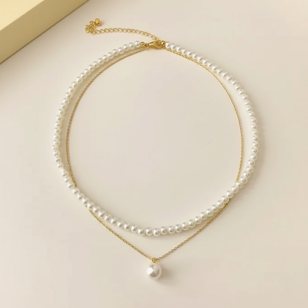 Double-layer white pearl pendant necklace with gold-plated chain on a warm ivory background