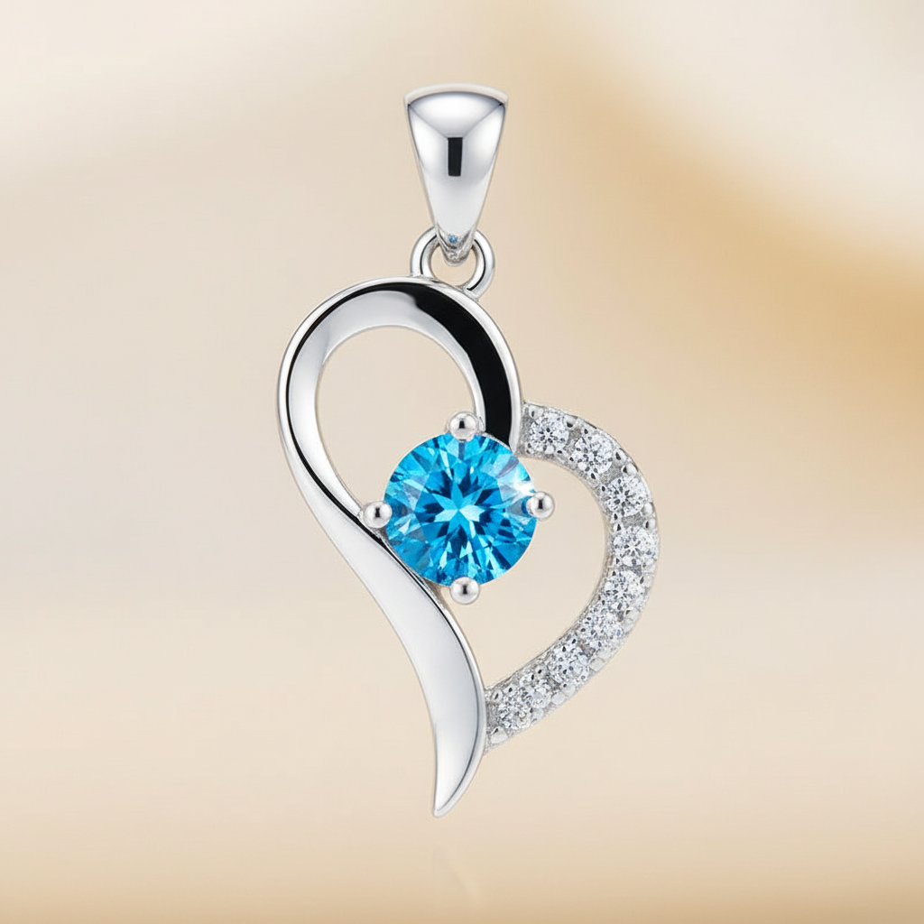 Close detail of a silver-tone heart pendant with a vivid blue faceted center stone and clear-stone edge