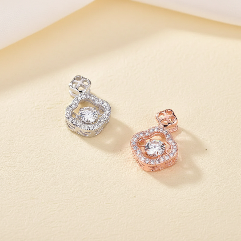 Platinum-tone and rose-gold clover pavé pendants arranged on warm ivory paper