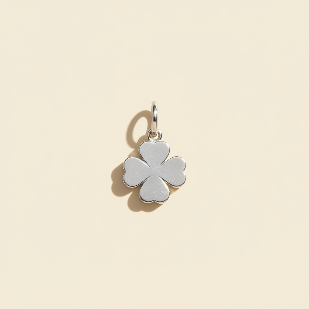 Silver four-leaf clover pendant on a warm ivory background