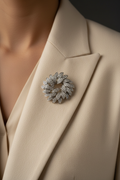 Silver-white leaf cluster brooch styled on the lapel of a warm ivory blazer