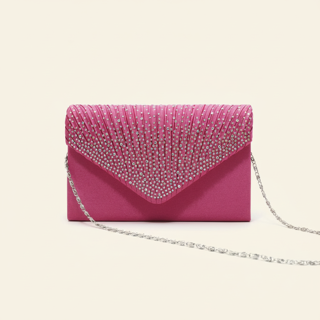 Pink satin envelope clutch bag with a pleated rhinestone flap and silver chain strap on a warm ivory background