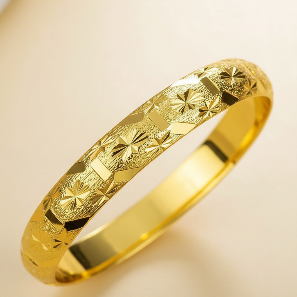 Close detail of engraved geometric and starburst motifs on a gold-tone bangle
