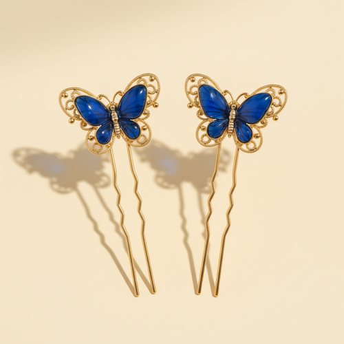 Pair of blue resin butterfly hair pins with gold-tone metal on a warm ivory background