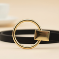 Close-up of the polished gold ring buckle and rectangular loop on the black leather strap