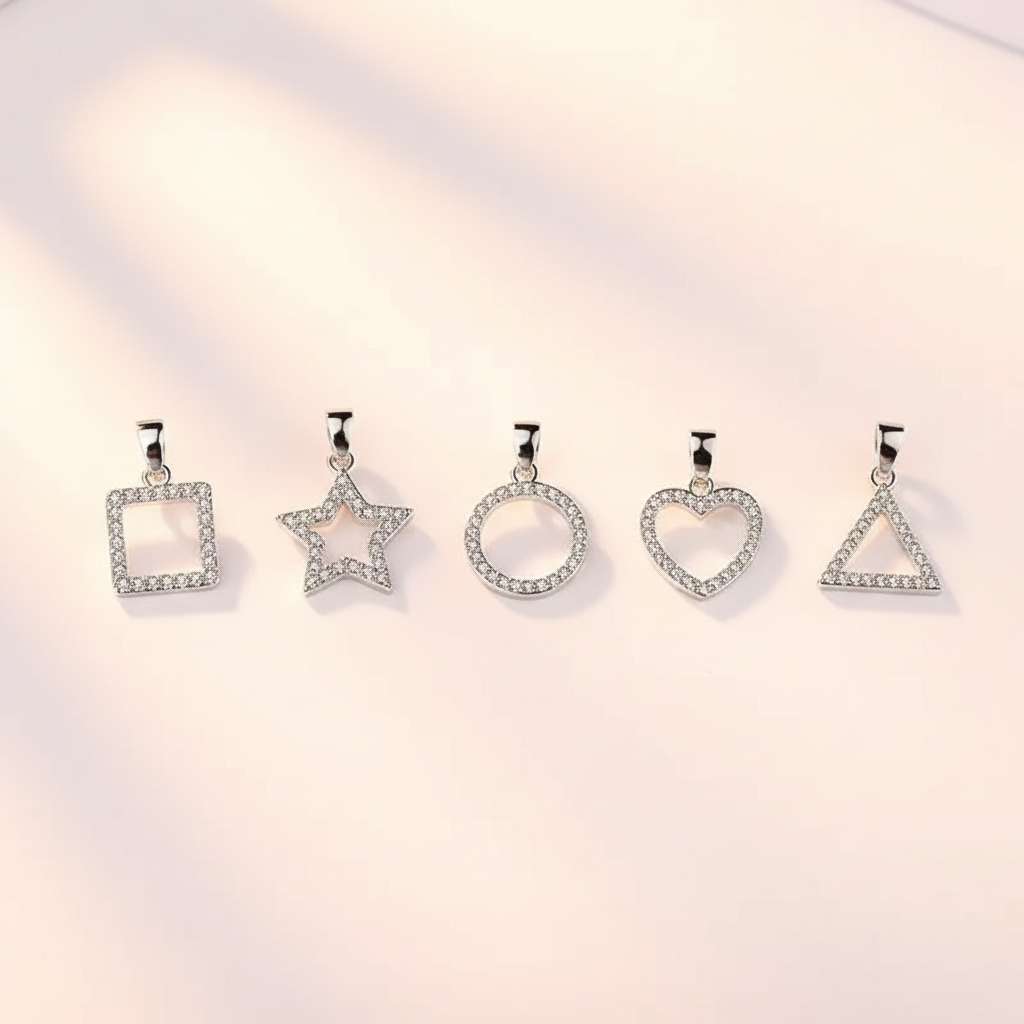 Five silver-tone geometric pendant charms in heart, star, round, square, and triangle shapes on a warm ivory background