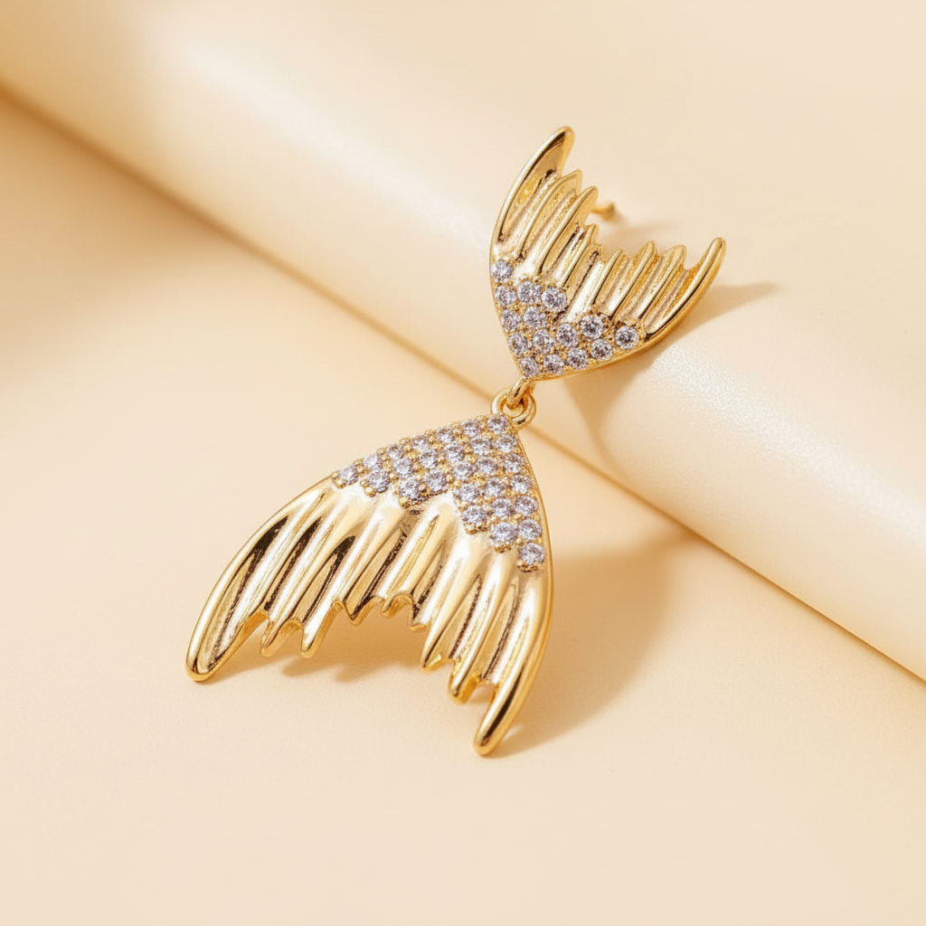 Close-up detail of pavé crystals and ridged gold fins on the mermaid tail earring