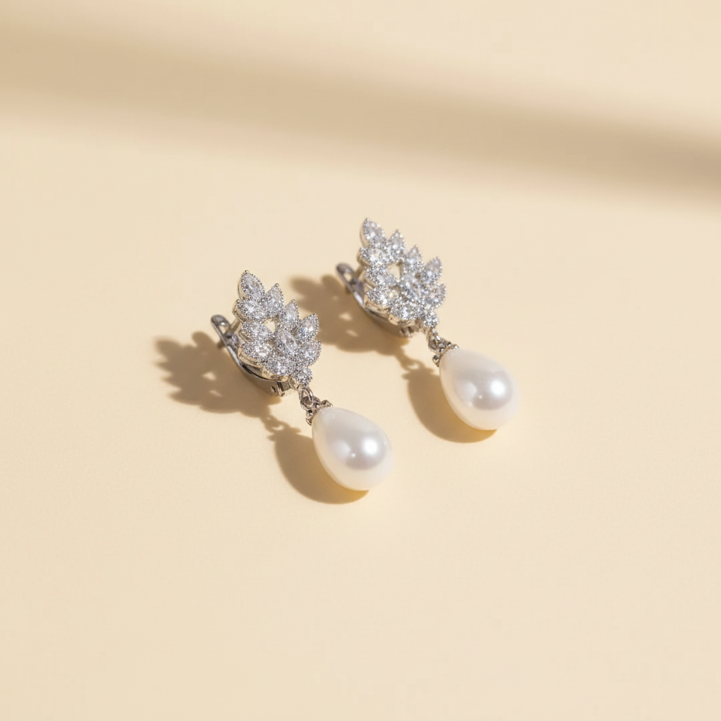 Pearl drop zircon earrings with leaf motif and teardrop pearls on a warm ivory background