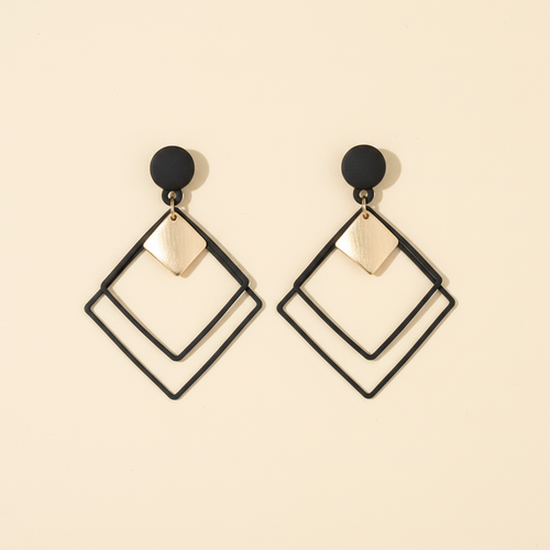 Pair of black and gold geometric square earrings on a warm ivory background