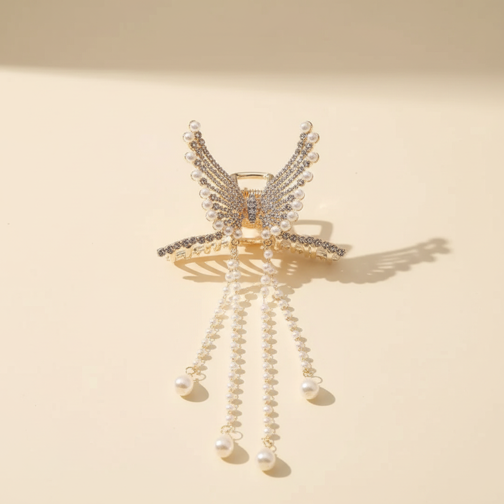 Golden zircon butterfly hair claw with pearl tassels on an ivory surface