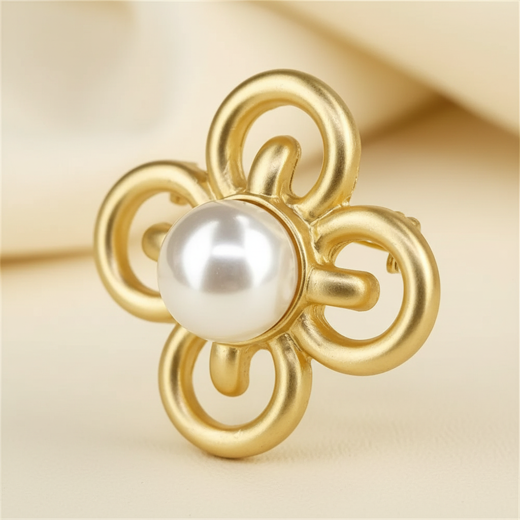 Close detail of a gold-tone four-leaf clover brooch with a round white pearl-style centerpiece