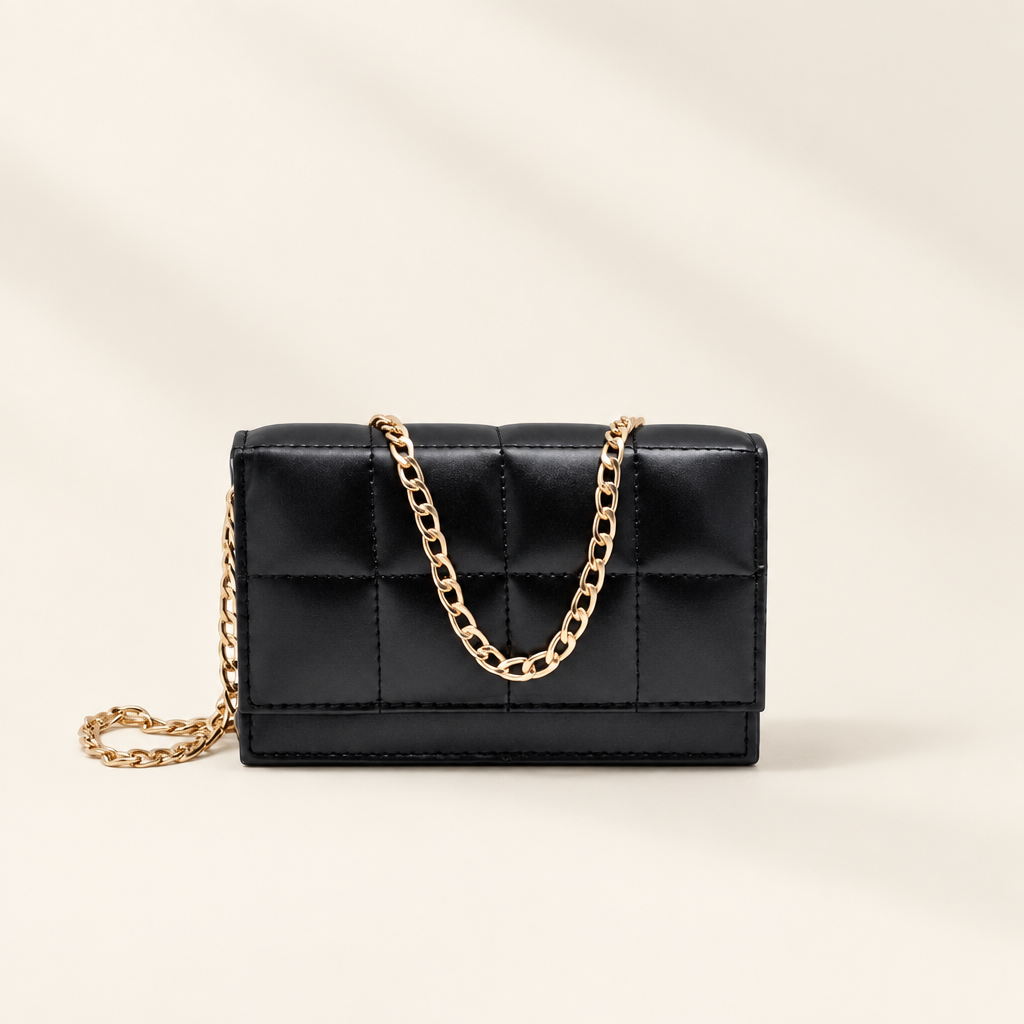 TAJIO black quilted crossbody bag with gold chain strap on an ivory backdrop