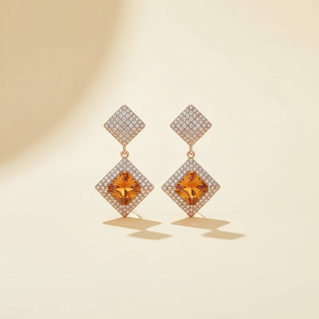 Golden crystal diamond-shape drop earrings on a warm ivory background