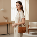Woman wearing a honey brown leather bow shoulder bag in a refined neutral interior