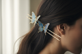 Blue and gold butterfly hair pins styled in swept-back dark hair