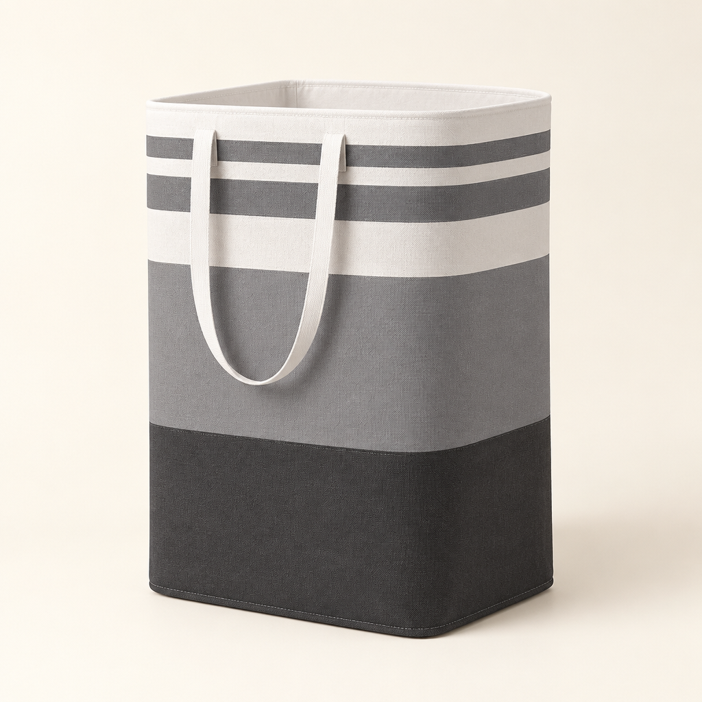 Foldable grey striped laundry basket with white handles on an ivory background