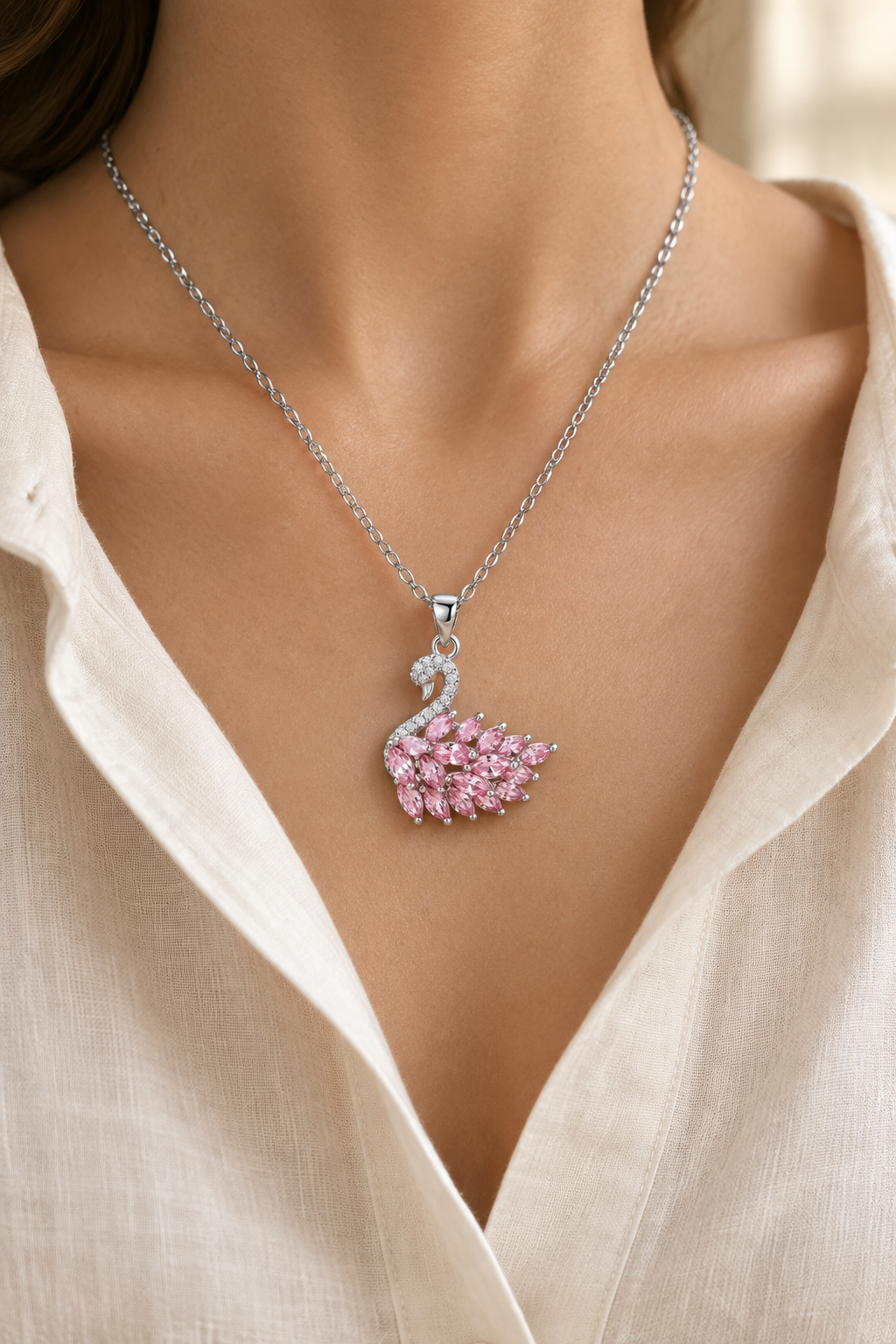 Pink swan pendant necklace with silver-tone chain worn with an ivory blouse
