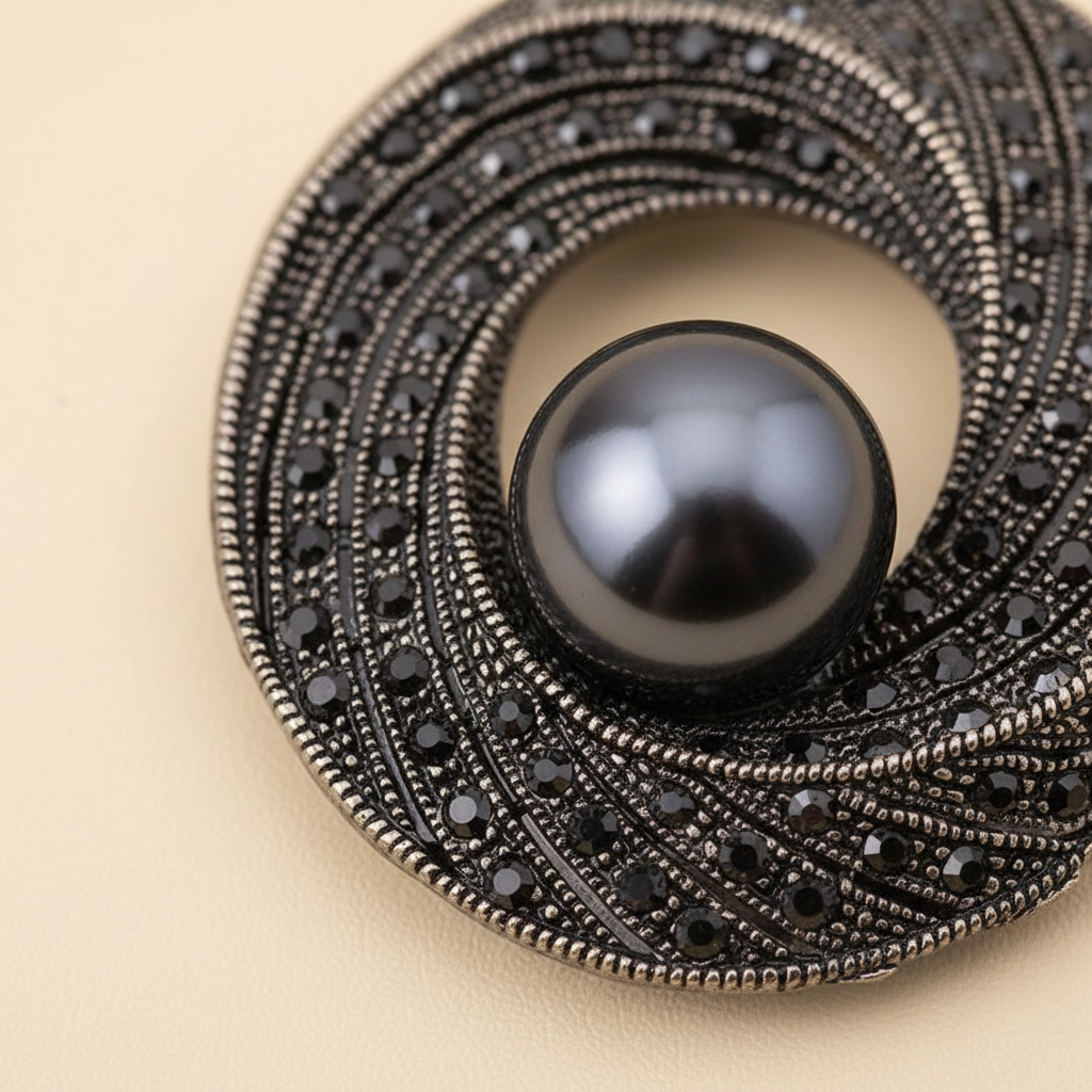 Close-up of black rhinestones and faux pearl on the swirl brooch
