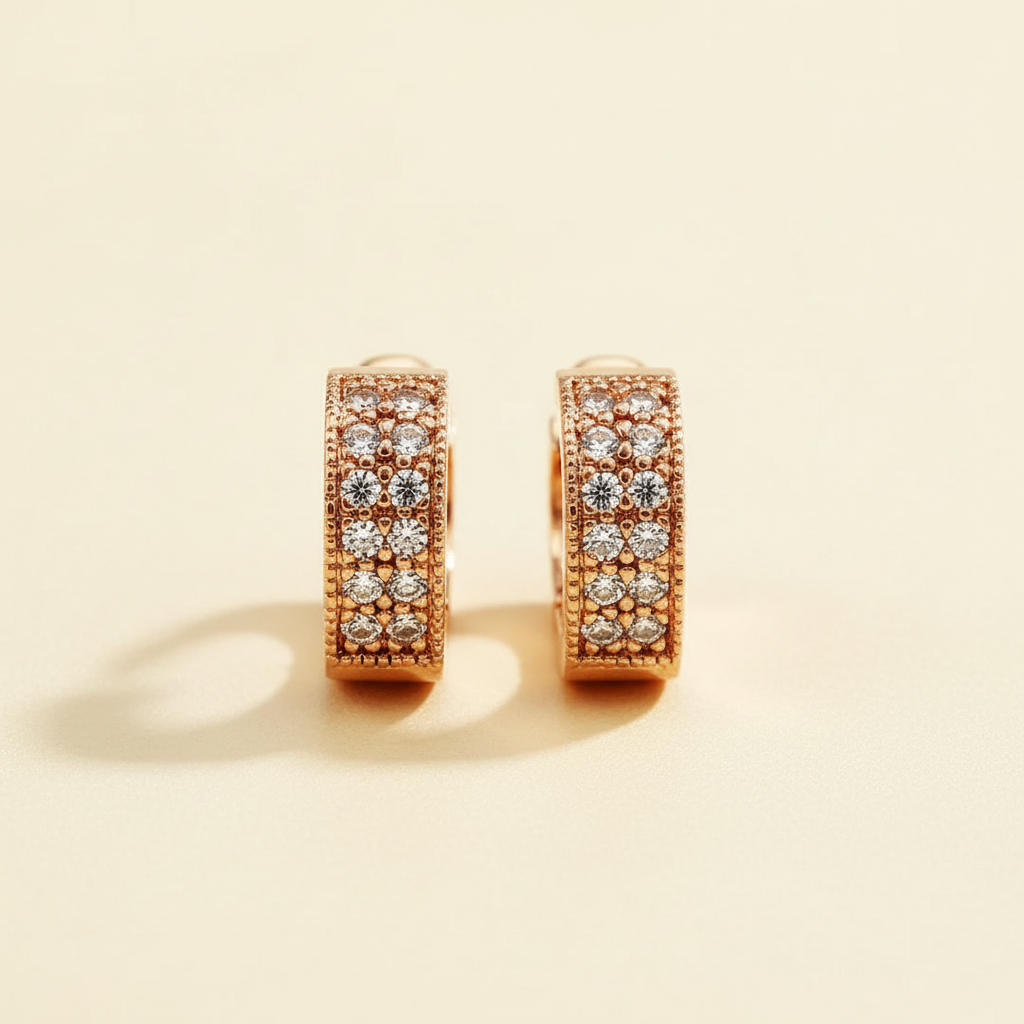 Rose gold pavé zircon huggie hoop earrings arranged on a warm ivory background