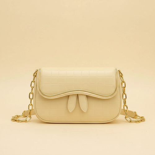 Beige leather shoulder bag with bow detail and chain strap on a warm ivory background