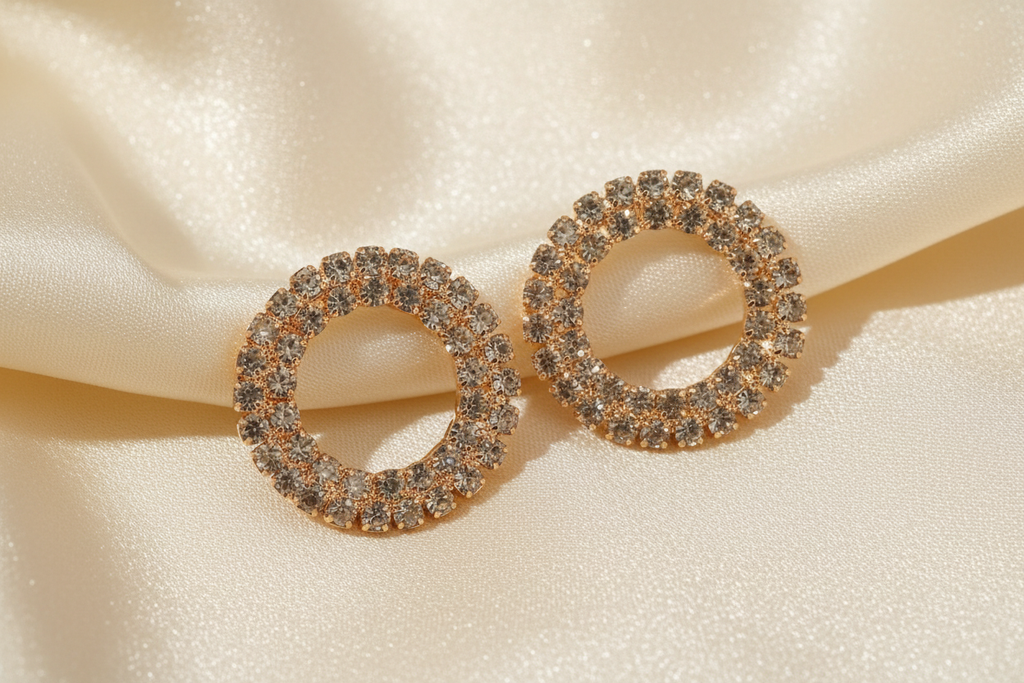 Close detail of round gold-tone crystal earrings on ivory silk