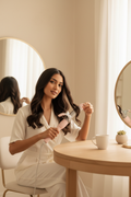 Woman styling dark hair with the RIWA blush pink and silver 32mm ceramic curling iron