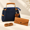 Navy blue structured handbag with tan pouch and detachable shoulder strap on ivory background