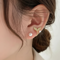 Model wearing the golden fish tail stud earring with pearl detail