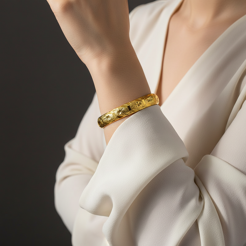 Woman wearing an engraved gold-tone bangle with a refined ivory sleeve