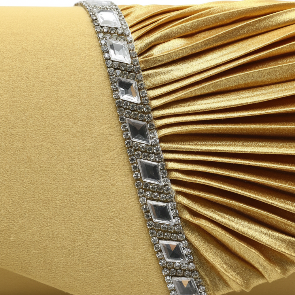 Close detail of the pleated gold fabric and rhinestone trim on an evening clutch