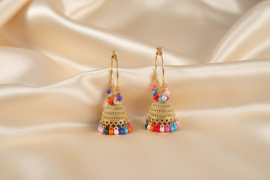 Golden jhumka earrings with multicoloured crystal tassels styled on ivory silk