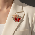 Red pearl and crystal butterfly brooch pinned to an ivory blazer